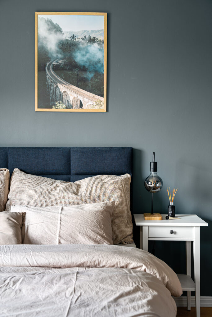 Seng med beige sengetøy og bilde over sengegavel